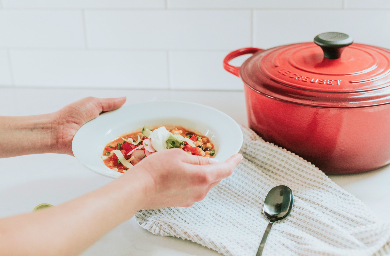 A Meal Train recipient at home filling a bowl of soup from a pot.